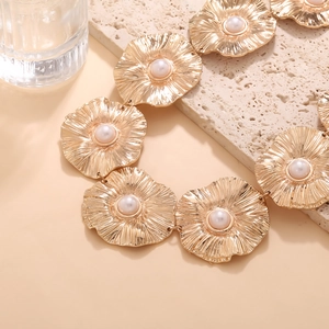 Detail of vintage gold flower necklace with pearls on a minimalist stone base