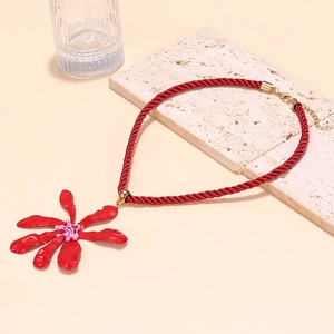Detailed macro view of the 3D red metallic flower pendant with woven cord on stone