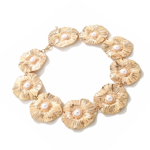 Vintage gold necklace with floral petal discs and white pearl centers on white backdrop