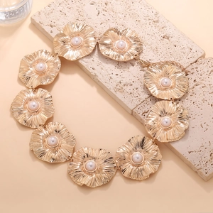 Vintage golden flower necklace with textured petals and faux pearl centers on beige stone