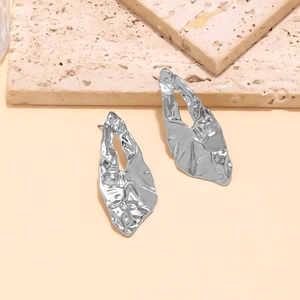 Detail of silver irregular geometric earrings with hammered texture and hollow design