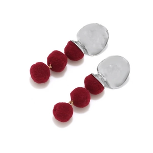 Chic silver hammered metal earrings with three red pom-poms in a vertical drop style