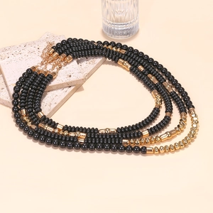 Detail of four-layer black and gold beaded necklace with adjustable metal clasp