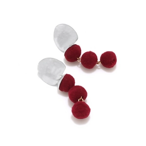 Close-up of burgundy fuzzy balls and hammered silver metal disk drop earrings