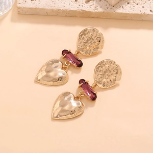 Macro detail of vintage gold tiered earrings with purple crystal and heart pendant
