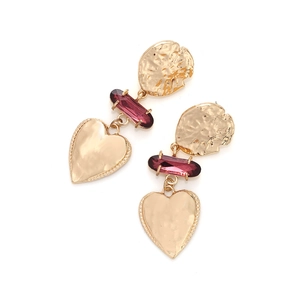 Detail view of vintage gold coin earrings with purple gemstone and heart shaped charms