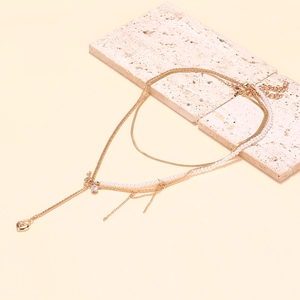 Close-up of layered gold chains with baroque pearls and a small heart pendant