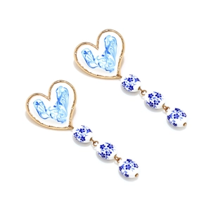 Detailed view of handmade blue and white enamel heart earrings with ceramic floral beads