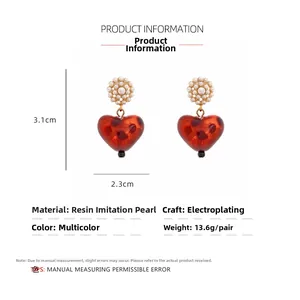 Close-up of heart-shaped leopard resin earrings with pearl flower studs and gold accents