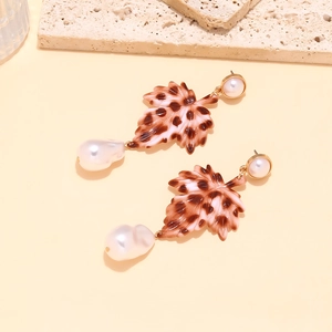 Détail de boucles d'oreilles perles baroques avec feuilles léopard et accents dorés