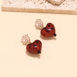 Detail of vintage heart earrings with faux pearl flower clusters and dark red resin