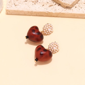 Detailed view of heart leopard resin earrings with elegant white pearl clusters on stone