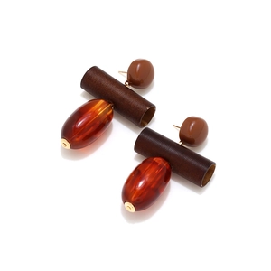 Macro detail of geometric drop earrings with wood beads and amber resin pendant