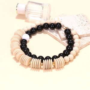 Double-layered geometric wood bead necklace with black and cream beads on a stone tray