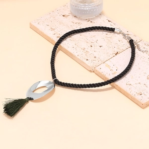 Détail d'un pendentif argenté géométrique avec frange vert foncé sur collier tissé