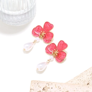 Detail of red enamel flower earrings with elegant hanging teardrop pearls