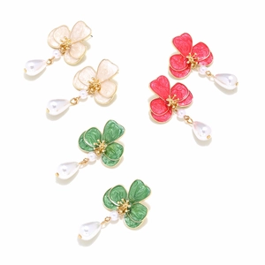 Three pairs of enamel flower earrings with pearls in cream, red, and dark green colors