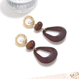Détail de boucles d'oreilles vintage géométriques léopard avec résine ambre et perles en bois