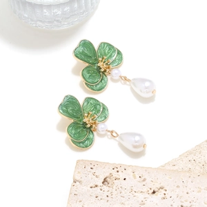 Detail of flower earrings with green enamel leaves and teardrop faux pearls on gold stems