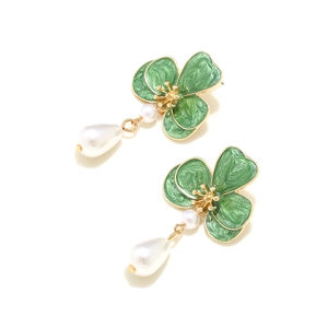 Detailed macro view of green enamel flower petals and elegant teardrop pearl drop earrings