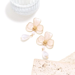 Macro detail of long flower earrings with pink enamel petals and teardrop pearl charms