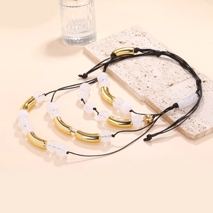 Detailaufnahme handgefertigter Perlenarmbänder mit Goldröhren und verstellbaren Knoten