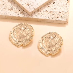 Close-up of vintage gold coin earrings with heart relief and irregular wax seal texture