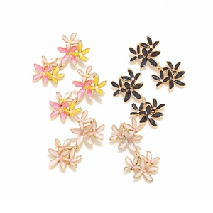 Détail macro de boucles d'oreilles fleurs en émail à trois niveaux avec bordure dorée