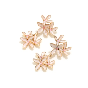 Détail de boucles d'oreilles pendantes fleurs roses en émail avec bords dorés