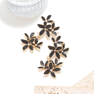 Détail de boucles d'oreilles fleuries faites main en émail noir et accents dorés