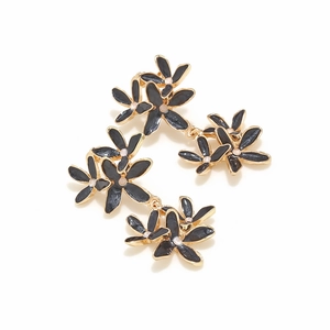 Gros plan détaillé des boucles d'oreilles fleurs en émail noir avec bords dorés et perles