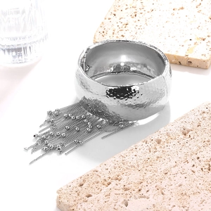 Detailed macro view of hammered texture silver bangle with delicate bead chain tassels
