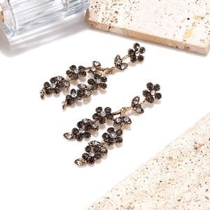 Detailed macro view of vintage gold hollowed floral earrings with crystals on stone base