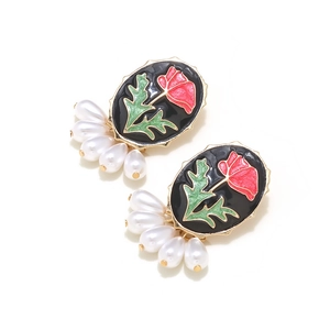 Detail of vintage enamel rose earrings with white teardrop pearls and golden scallop trim