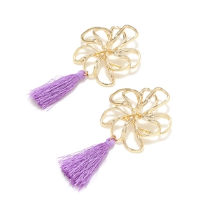 Detailed close-up of golden hollow flower earrings with purple silk thread tassels
