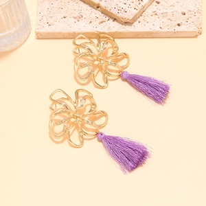 Close-up of golden hollow flower earrings with elegant long purple thread tassels