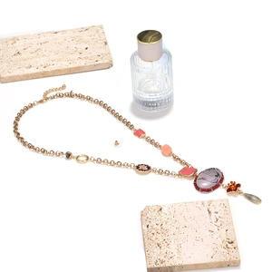 Detailed view of bohemian floral crane pendant necklace with pink enamel and matching earrings