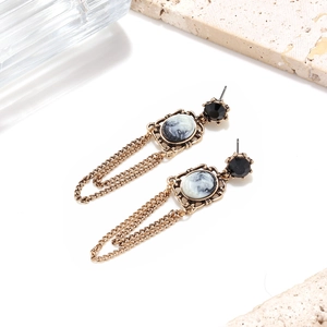 Detailed macro of vintage baroque earrings with cameo pendant and cascading gold tassels
