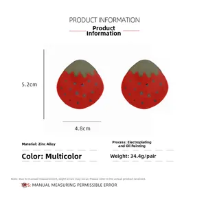 Vue détaillée des boucles d'oreilles fraise en émail rouge avec feuilles et points