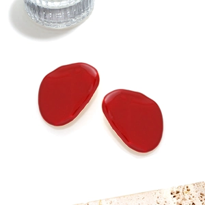 Exaggerated geometric red enamel stud earrings with gold base on a minimalist white stone background
