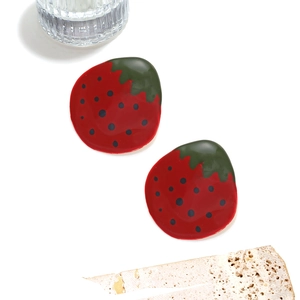 Boucles d'oreilles fraises rouges avec feuilles vertes et pépins noirs sur fond blanc