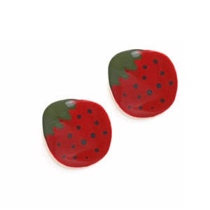 Gros plan de boucles d'oreilles fraises en émail avec feuilles vertes sur fond blanc