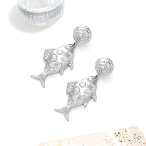 Detailed close-up of silver vintage fish drop earrings on a minimalist stone background