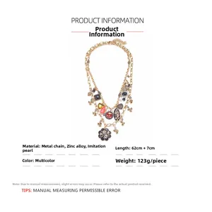 Detail view of layered gold necklace featuring enamel flower and white faux pearls