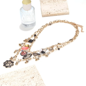 Detail of layered gold necklace with black enamel flowers and vintage heart pendants