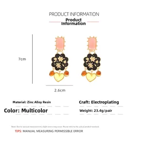 Vue détaillée des boucles d'oreilles en résine avec fleurs et cœurs et dimensions