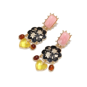 Détail de boucles d'oreilles vintage avec fleurs en résine et breloques cœur