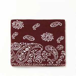 Détail d'un cache-cou en tricot rouge foncé avec motifs cachemire blancs et texture épaisse