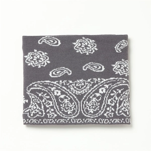 Détail d'un cache-cou en maille gris foncé avec motifs jacquard paisley blancs
