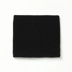Detail of black knitted neck warmer with ribbed edges showing soft texture and density